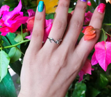 Close up of sterling silver ring on woman's left hand ring finger. Ring is adjustable with cat shape on one end. Looks like a cat with a long tail. 