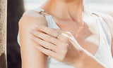 Silver ring with cat shape on pointer finger of woman. Woman holding hand to shoulder with ring on her finger. 